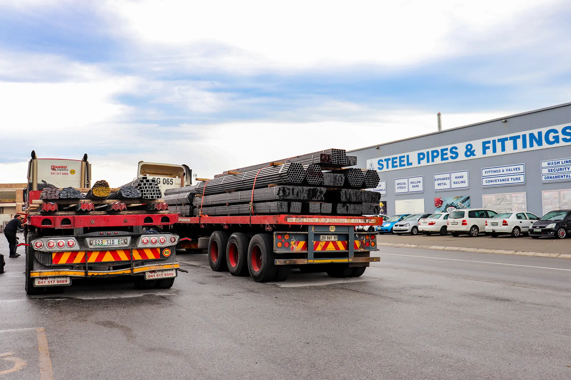 Loaded steel trucks in front of the Steel Pipes & Fittings building in Korsten