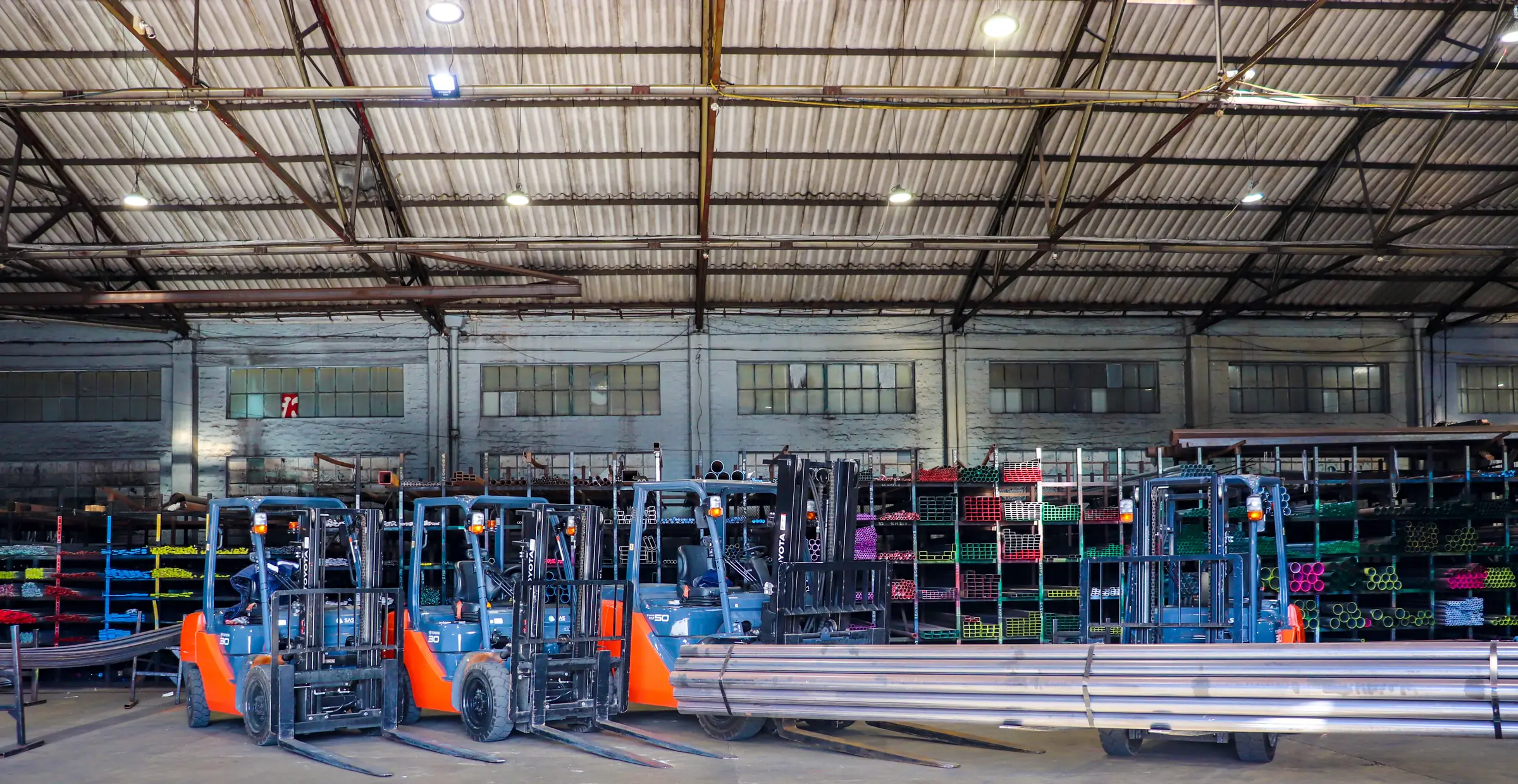 Forklifts in front of colour-coded steel tube racking